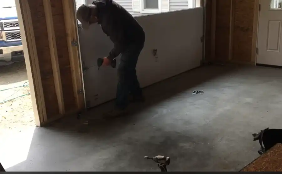 Technician installing a new garage door panel into a framed garage opening