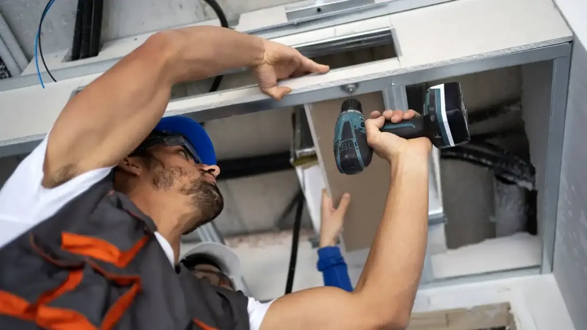 Technician repairing a garage door track and spring mechanism in Visalia, CA
