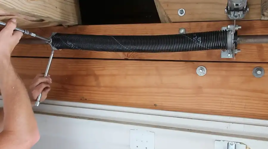 Torsion spring being wound with winding bars during a garage door spring replacement