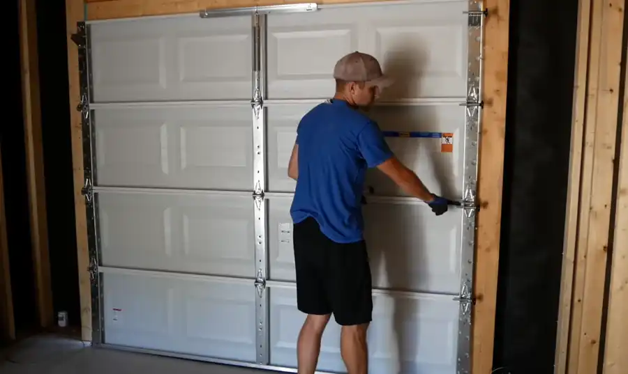 Garage door repair technician installing hardware on a new white panel garage door in Visalia, CA