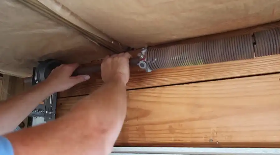Close-up of hands adjusting a garage door torsion spring during a repair in Visalia, CA